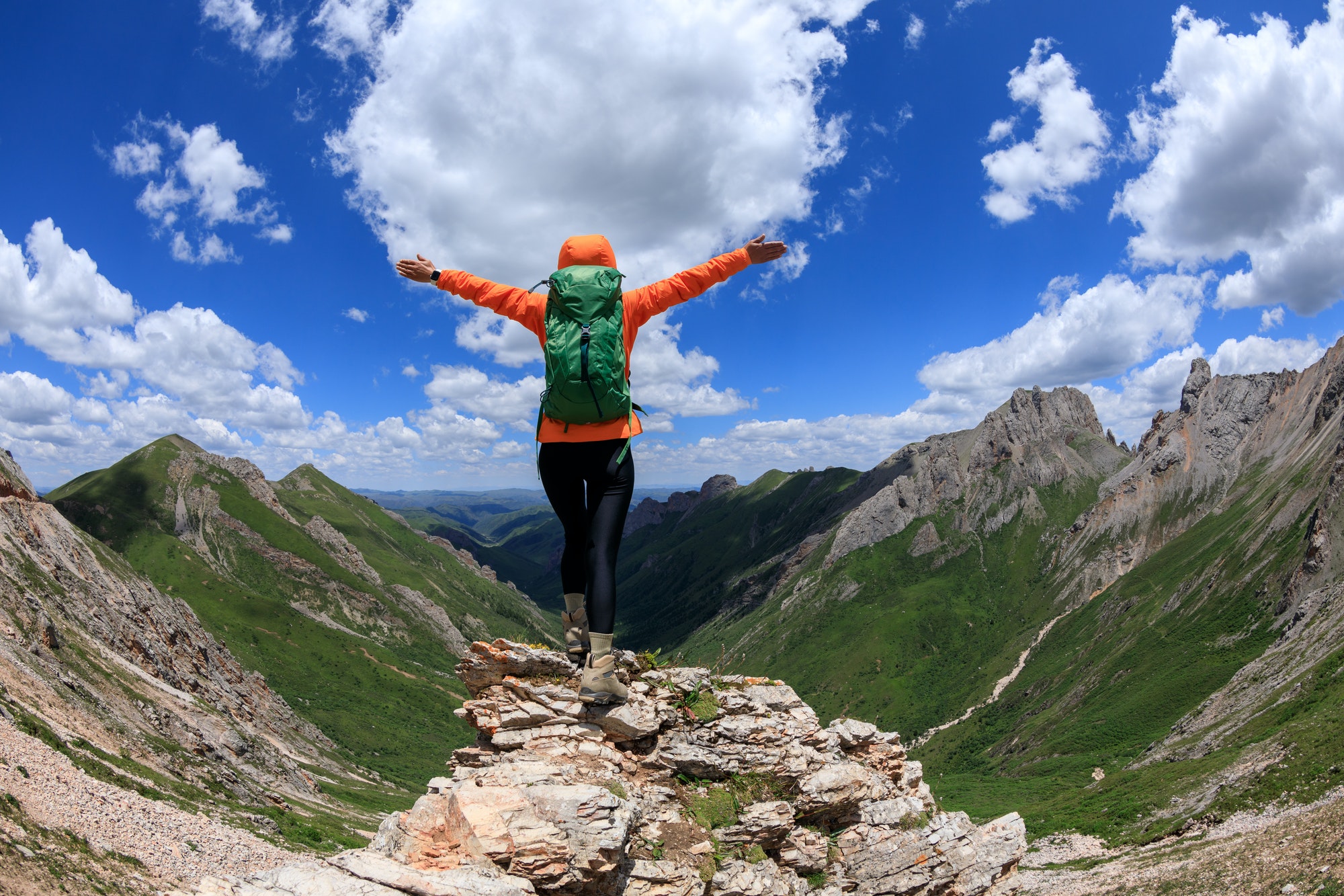 Successful woman backpacker hiking on alpine mountain peak Successful woman backpacker hiking on alpine mountain peak